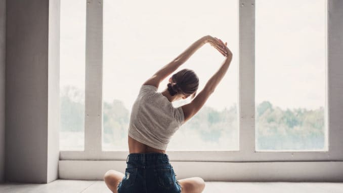 Woman doing exercises at home. Girl training and practicing yoga at class. Harmony, balance, meditation, relaxation, healthy lifestyle concept Persona esegue esercizi di stretching davanti a una finestra
